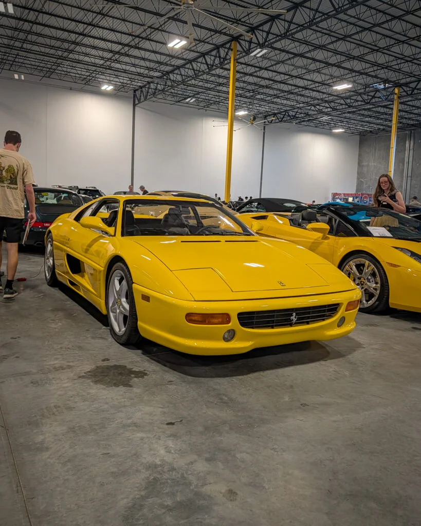 Yellow Ferrari sports cars parked indoors with people nearby