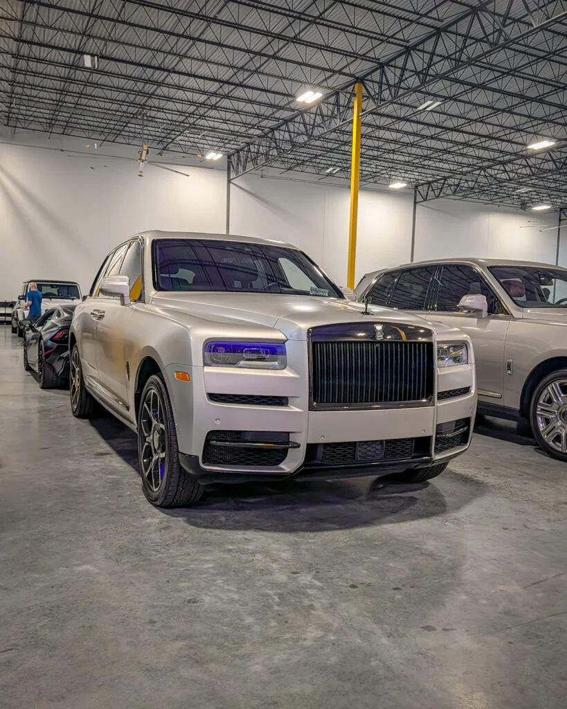 Silver Rolls-Royce Cullinan SUV front 3/4 view indoors with other vehicles in the background