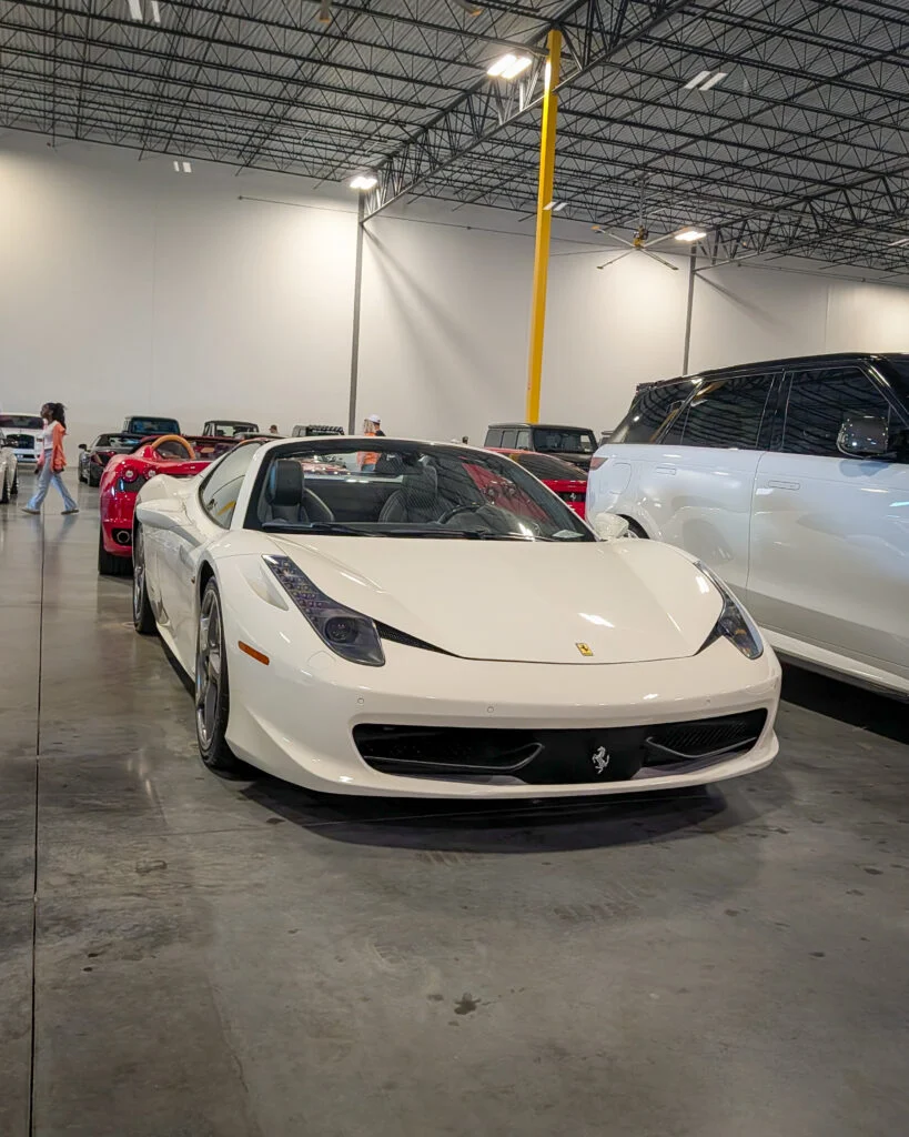 White Ferrari 458 Spider convertible in indoor car event with other vehicles in background