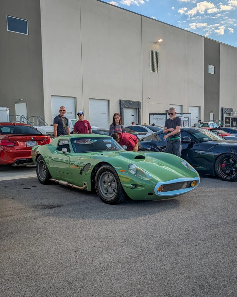 Green Novetta Coupe at an outdoor car meet with people standing and looking at it during daylight