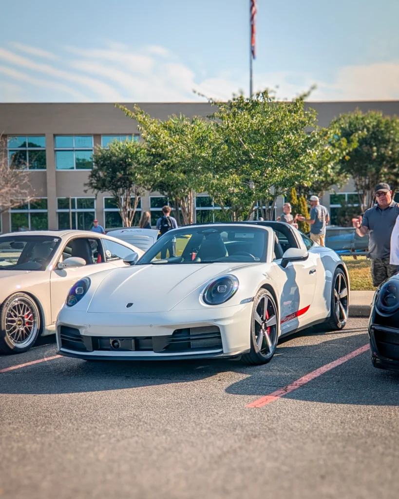 White Porsche 911 convertible parked outdoors on a sunny day with people and other cars in background