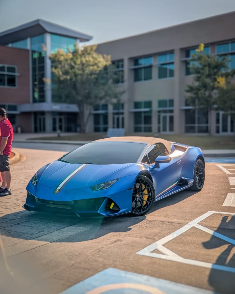 Blue Lamborghini Huracan with tan convertible top parked in front of commercial building