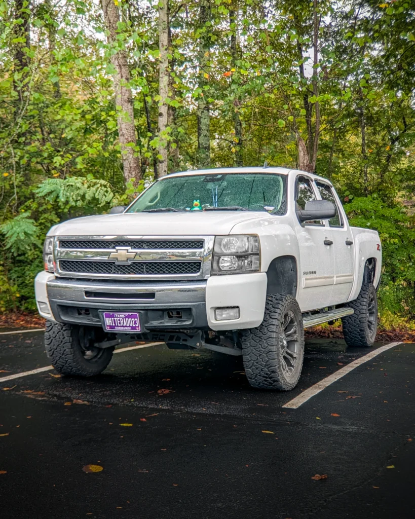 White Chevrolet Silverado pickup truck parked with trees in the background