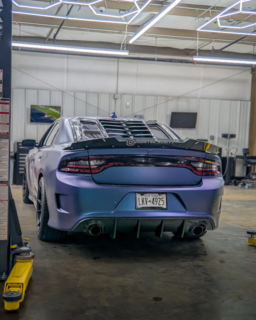 Rear view of matte purple Dodge Charger with rear window louvers inside a garage