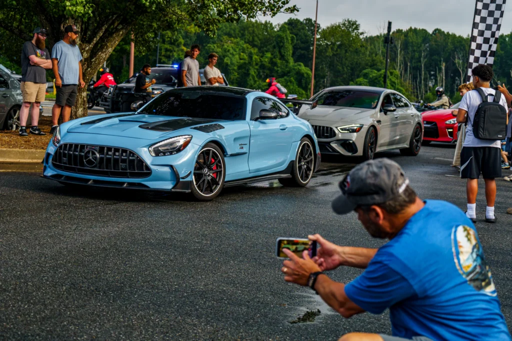 Light blue Mercedes-Benz AMG GT Black Series coupe at car event with white Mercedes-AMG and red Nissan GT-R in background