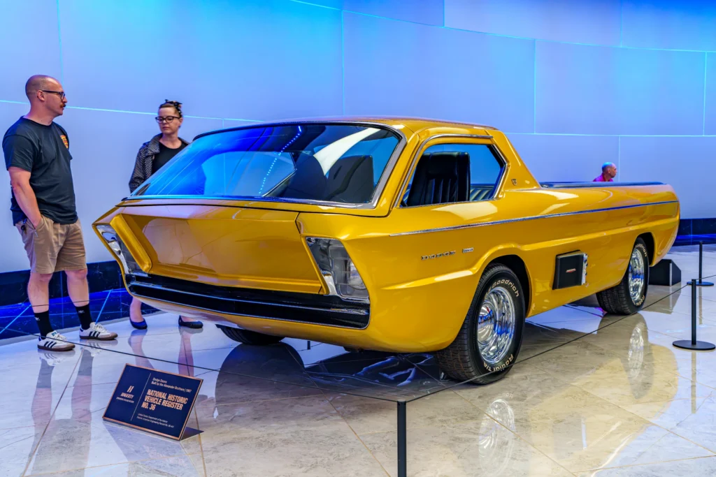 Yellow Dodge Deora pickup with two people standing next to it indoors under blue lighting