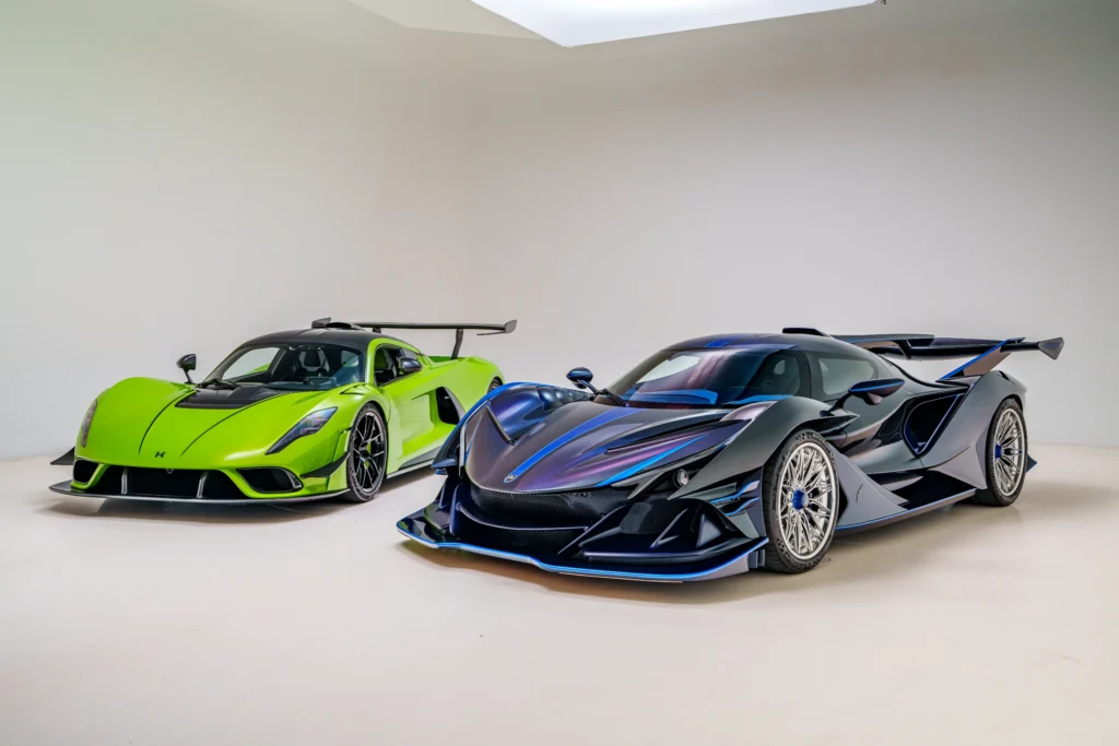 Green Hennessey Venom F5 and black Apollo IE parked indoors with white background