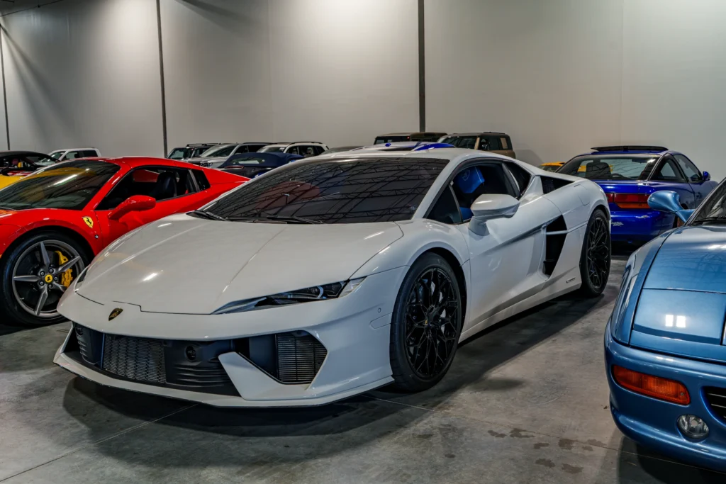 White Lamborghini Huracan in an indoor showroom with a red Ferrari and a blue Acura NSX nearby