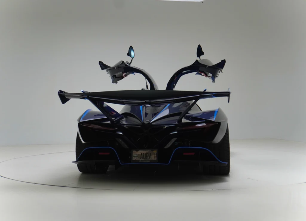 Rear view of a blue Apollo IE with butterfly doors open in a white studio.