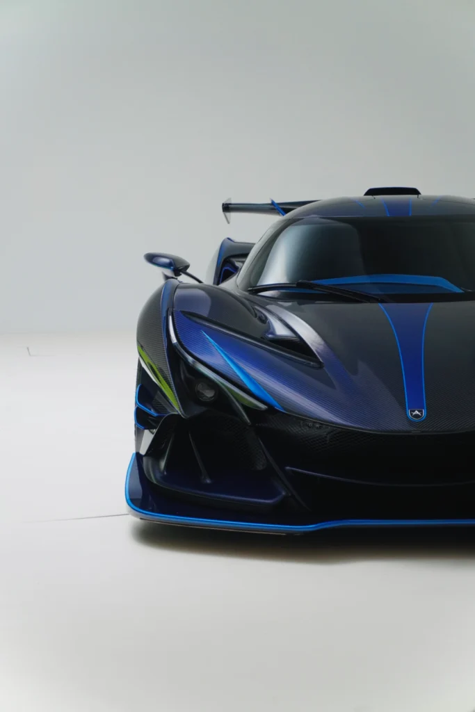 Front portion of a blue and black Apollo IE with aerodynamic design and racing wing in a plain studio