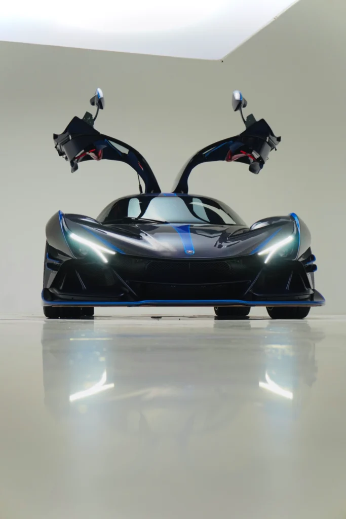 Black Apollo IE with blue accents and butterfly doors open indoors on a reflective floor
