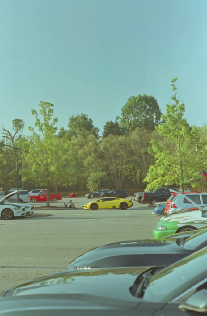 Yellow Lamborghini Huracán parked in a parking lot with other vehicles and trees in the background