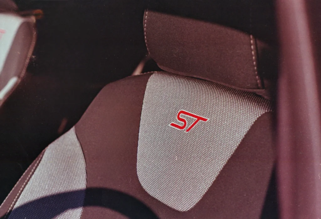 Close-up of a car seat with gray fabric and red ST logo embroidered