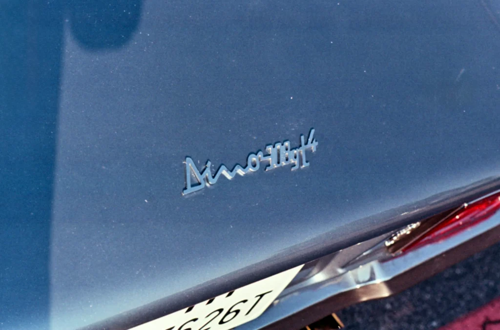 A Dino 308 GT4 badge sits on a blue rear deck above a chrome bumper and a partially visible taillight.