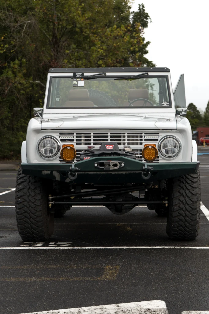 White Ford Bronco front view in parking lot with trees in background
