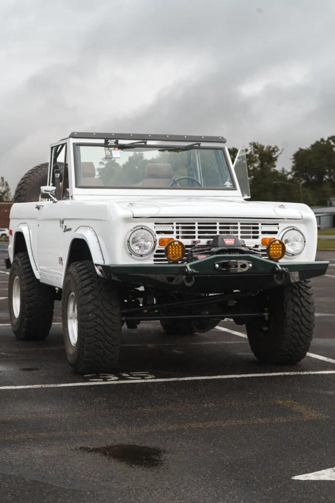 White Ford Bronco convertible parked on asphalt under a cloudy sky