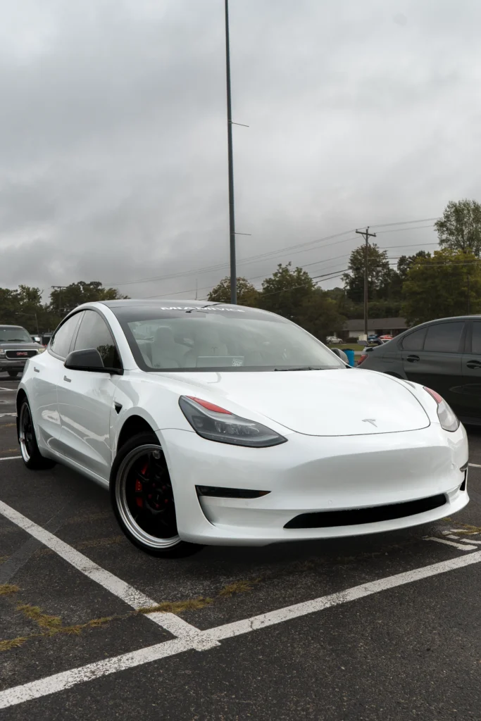 White Tesla Model 3 parked in an outdoor lot under overcast sky