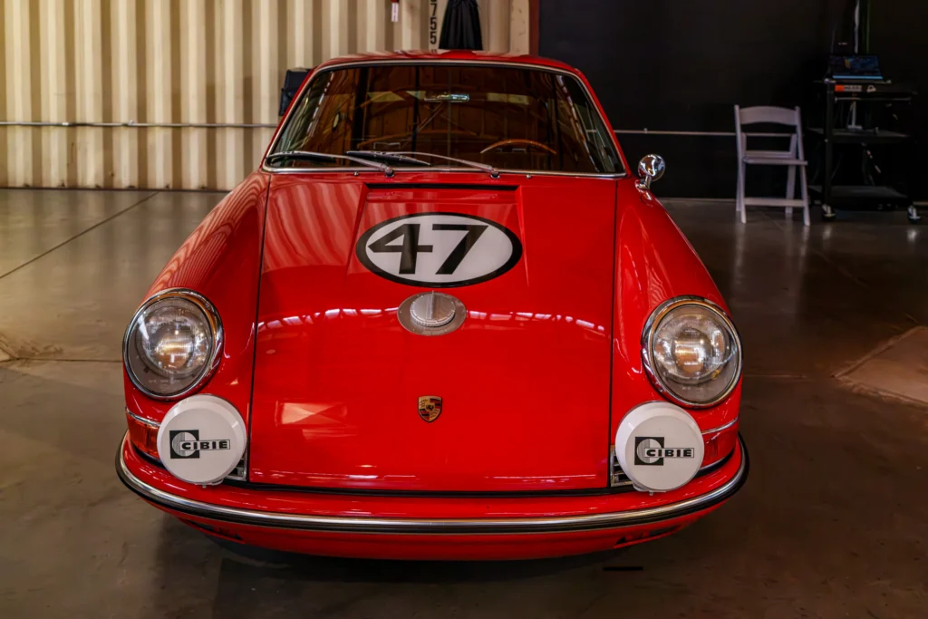 Red Porsche with number 47 decal on hood in indoor garage